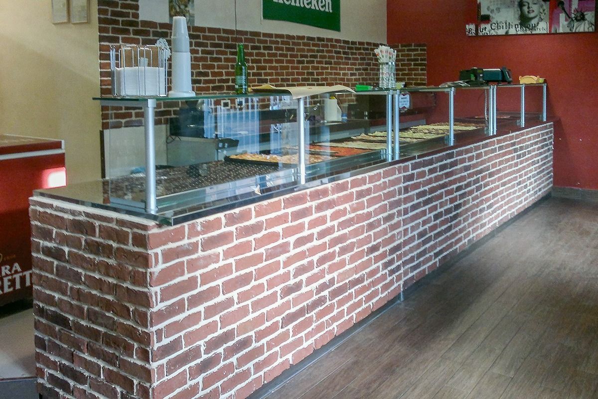 Brick-and-glass cafeteria counter with serving trays and a wood floor