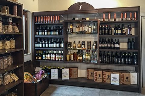 Wooden wine display with shelves of bottles and gift boxes in a shop interior