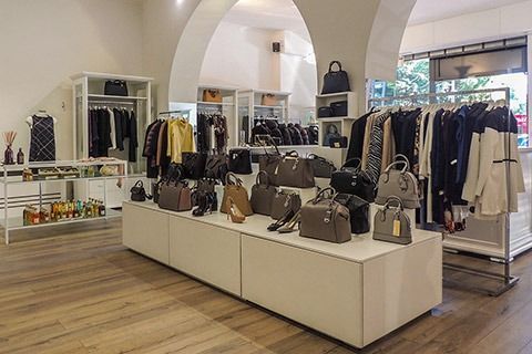 Boutique interior with handbags on display tables and clothing racks under arched ceilings