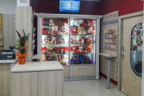 Gift shop display with shelves of red-and-white plush toys and a counter in the foreground