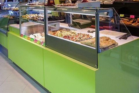 Green bakery display case with assorted pastries in a shop interior