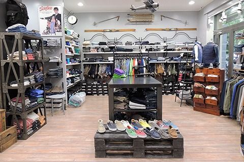 Shoe store interior with shelves of footwear, a central display table, and rows of shoes on the floor