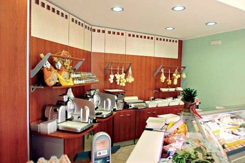 Coffee shop counter with espresso machine, pastries, and hanging cups against wood-paneled walls