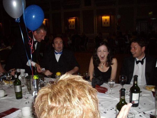 A group of people sitting at a table with wine bottles and balloons