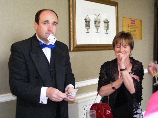 A man in a tuxedo is holding a card in his mouth