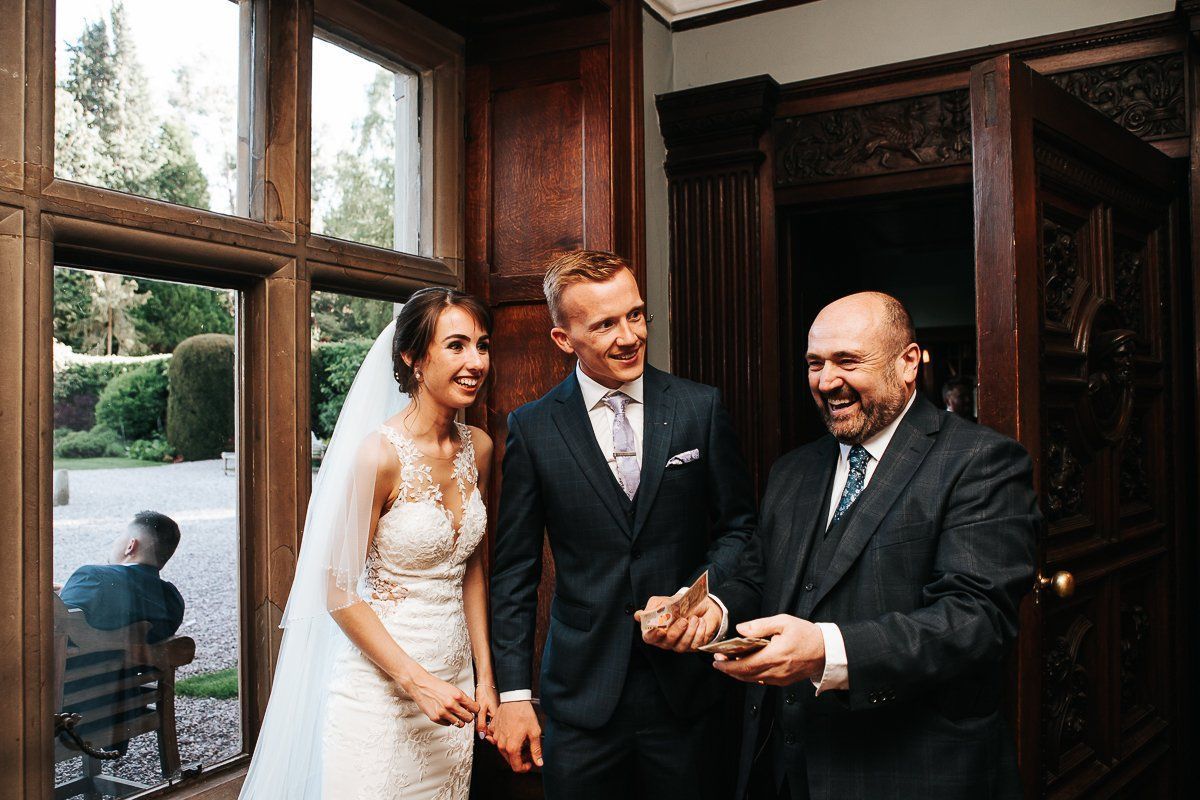 A bride and groom are posing for a picture with a man in a suit.
