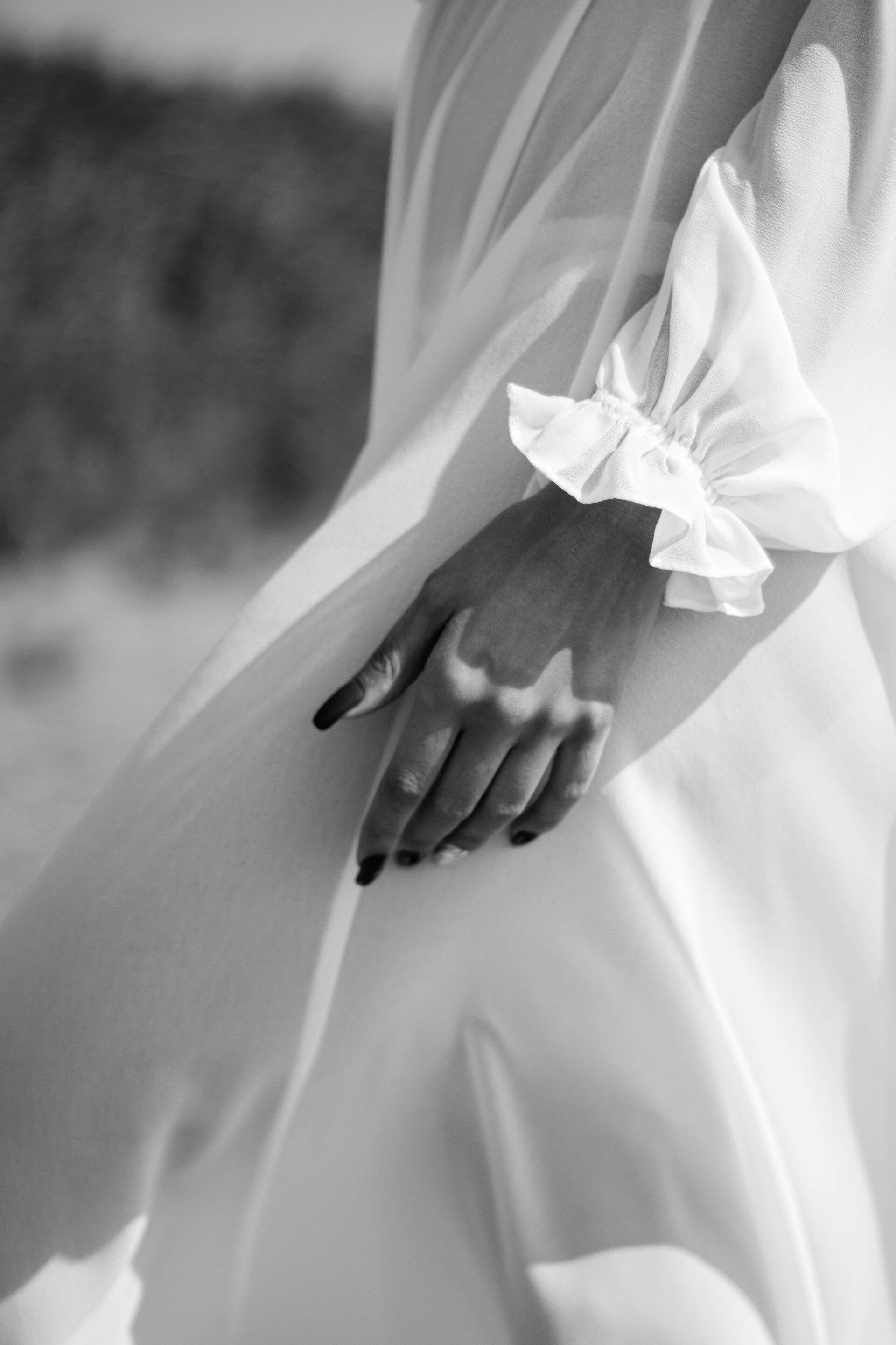 A black and white photo of a woman 's hand with a ring on it.