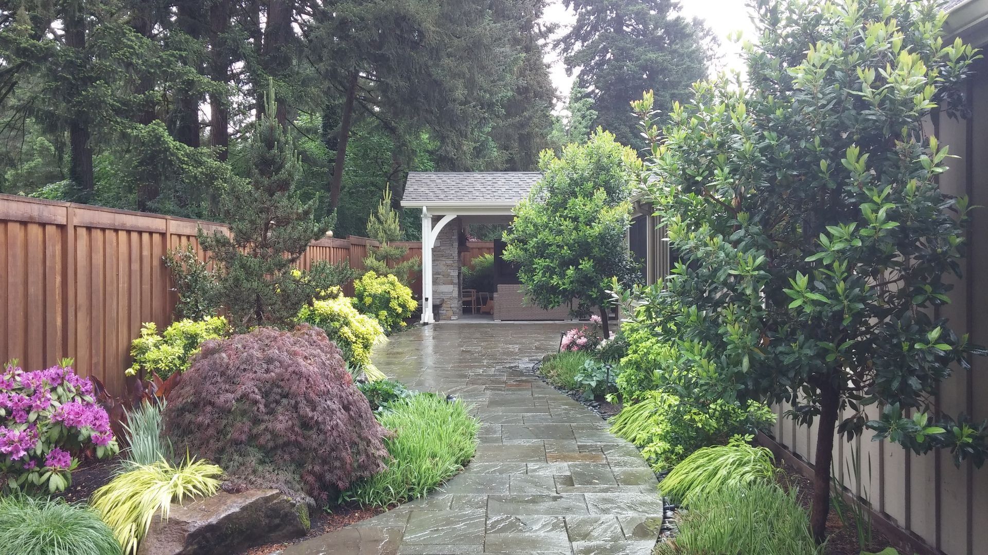 A path leading to a house with a wooden fence and trees