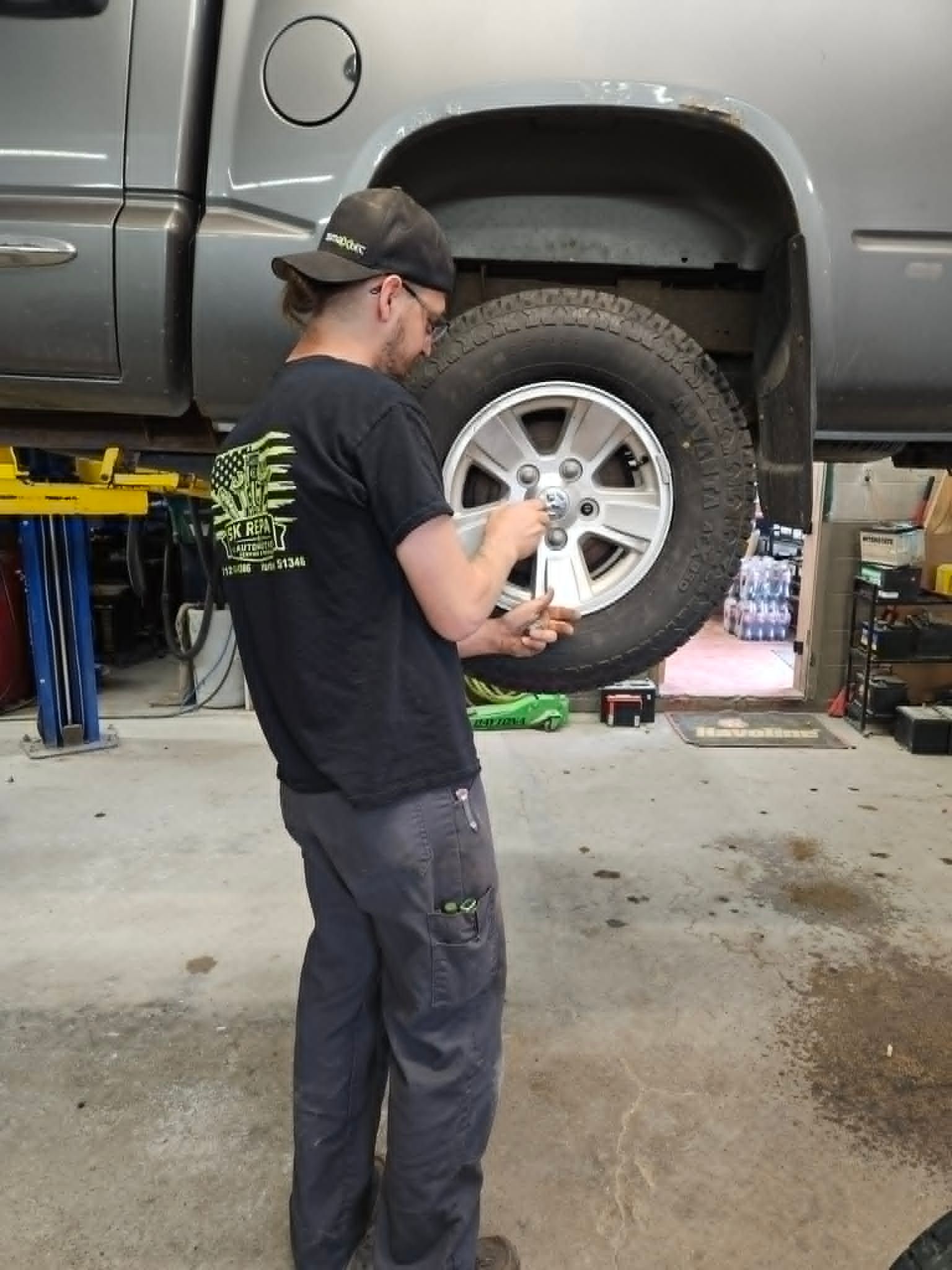 Mechanic inspecting a truck tire on a lift in an auto shop