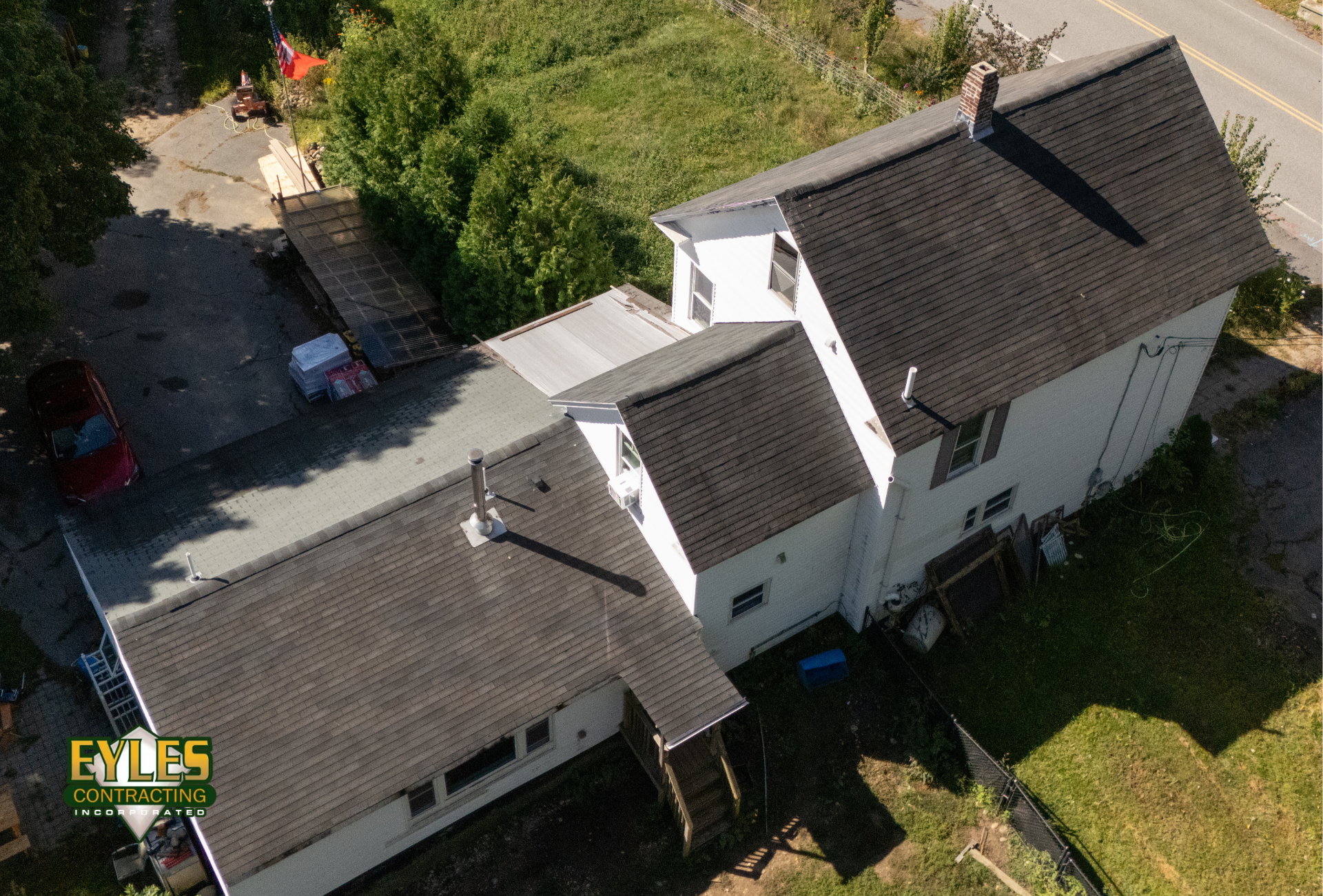 An aerial view of a residential home with an aging asphalt shingle roof showing visible wear.