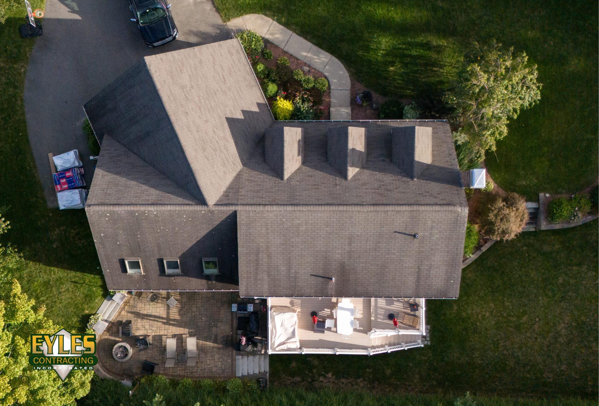 An aerial view of a large residential home with a multi-section asphalt shingle roof