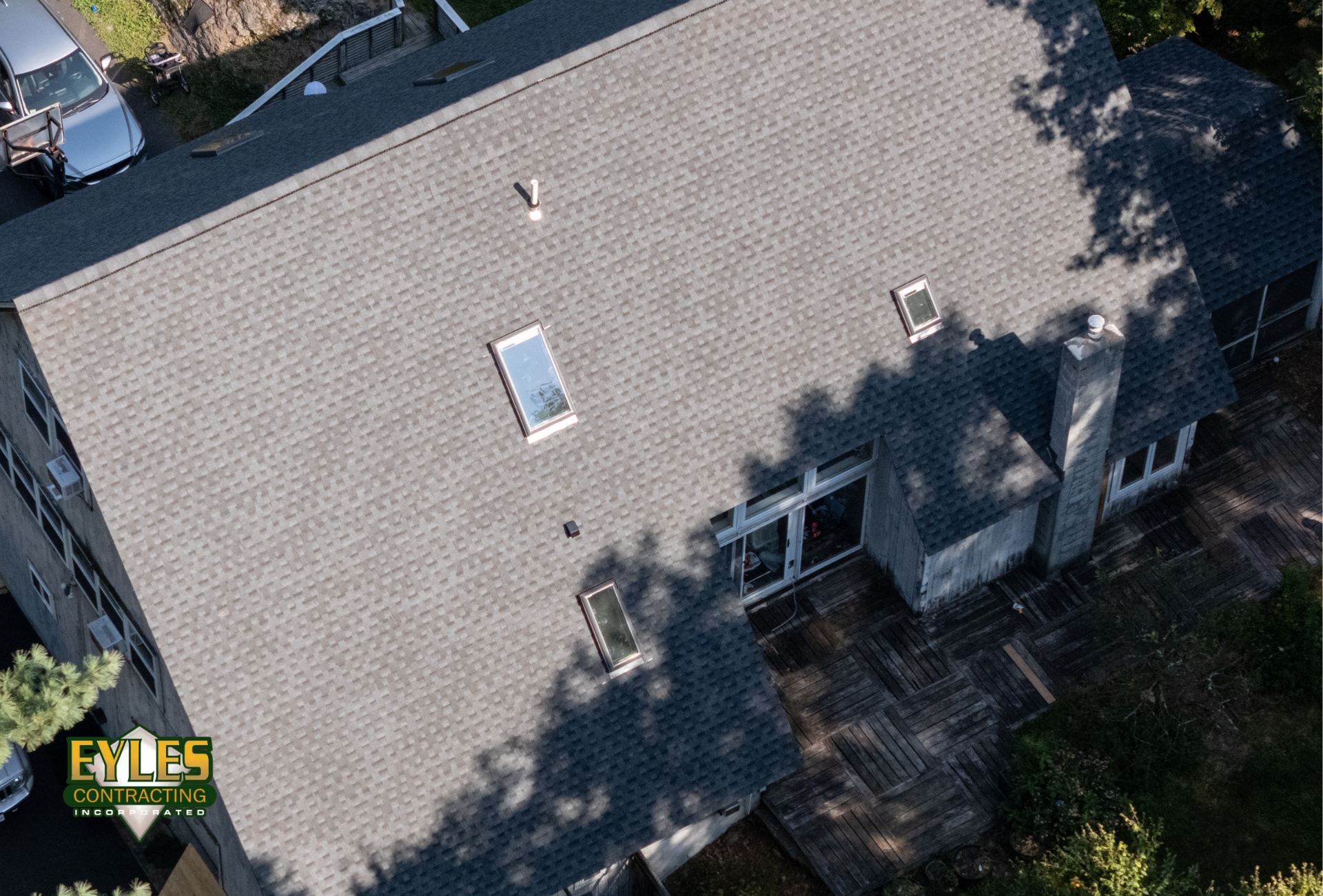 A residential roof with architectural shingles featuring an installed skylight.
