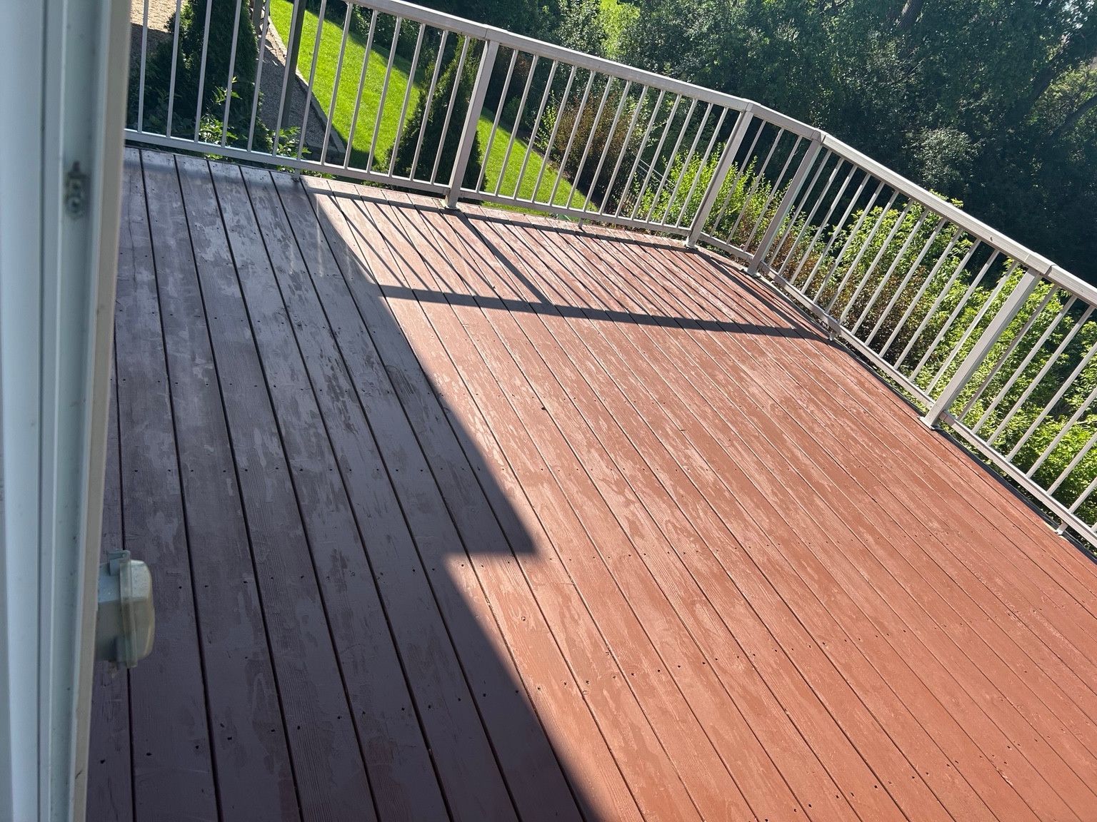 Wood deck surface with a reddish-brown finish and white railings.