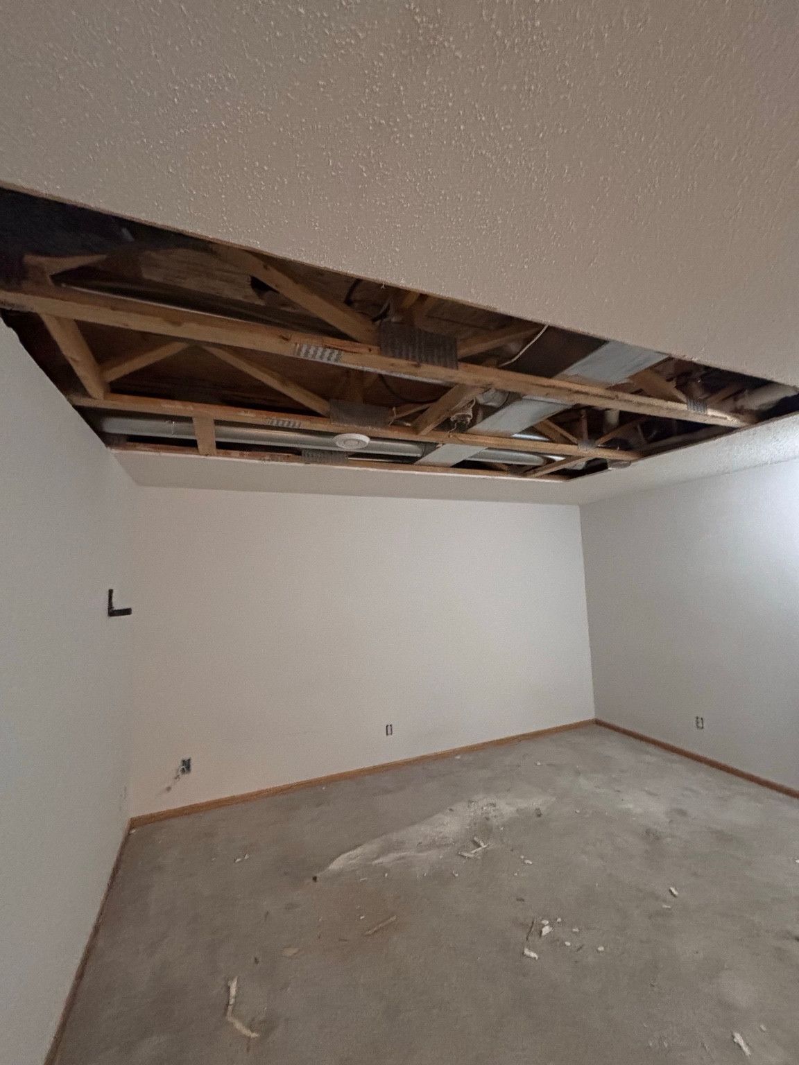 Ceiling opening exposing wood framing and ductwork during interior repair.