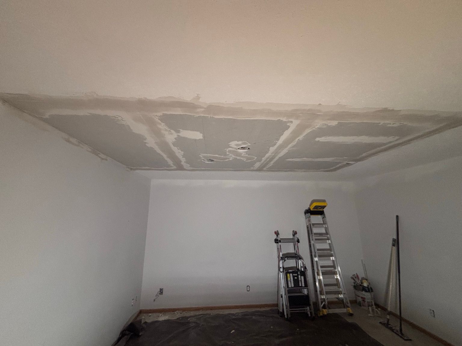 Drywall ceiling patch with joint compound along the seams.