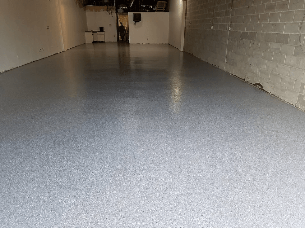 a garage with a concrete floor and a brick wall .