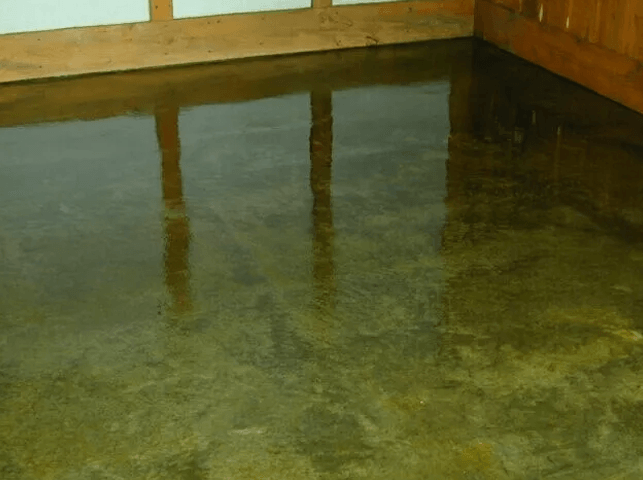 a room with a concrete floor and a wooden wall