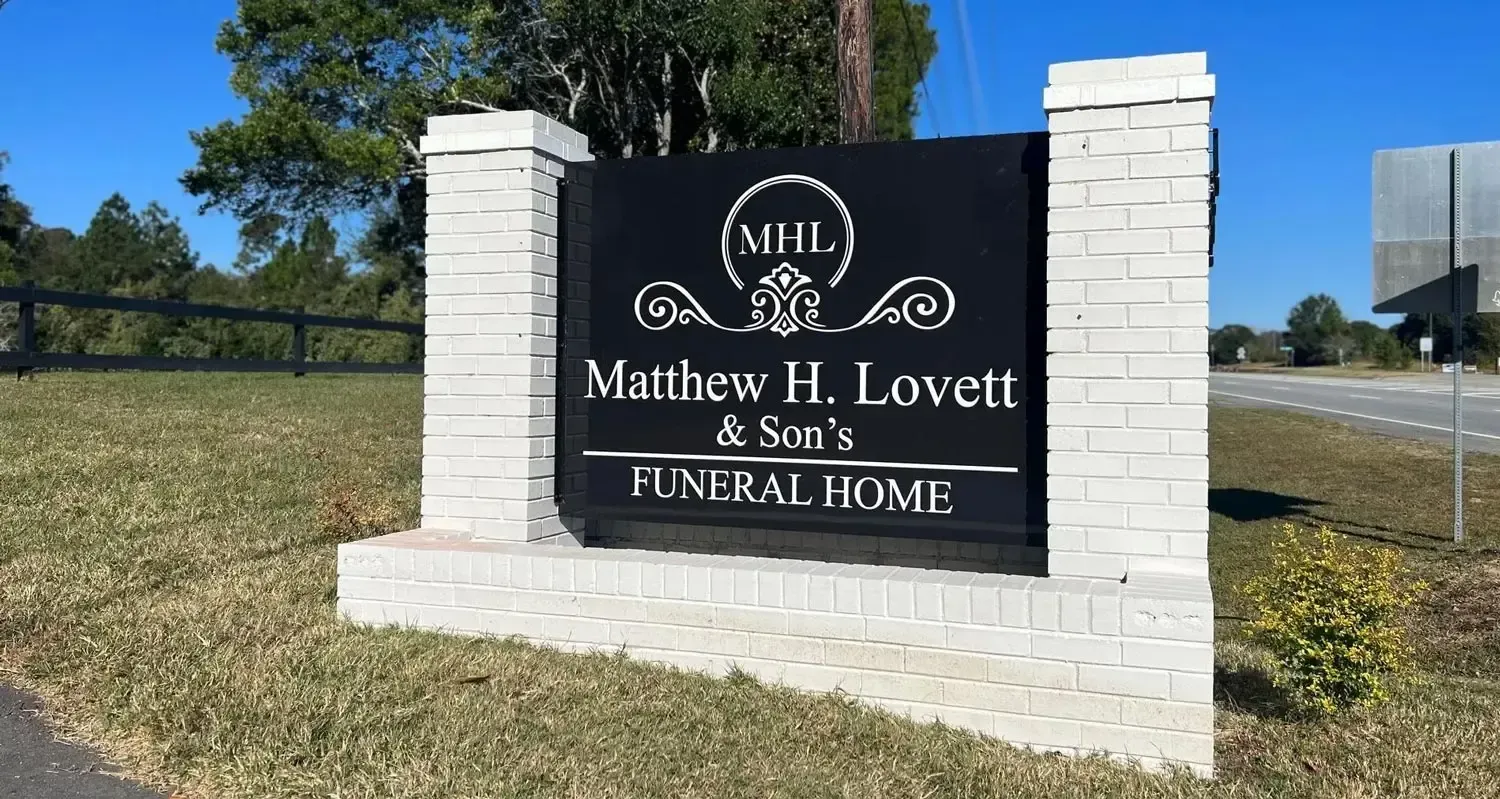 MHL Matthew H. Lovett & Sons Funeral Home sign on a brick monument by a roadside