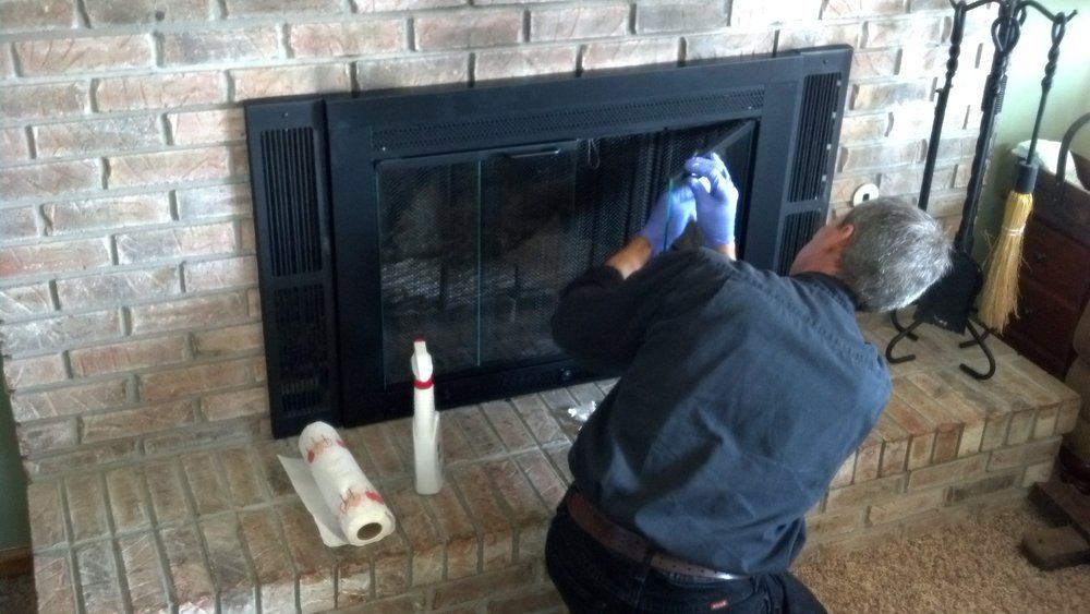 A man is cleaning a fireplace with gloves in a living room.