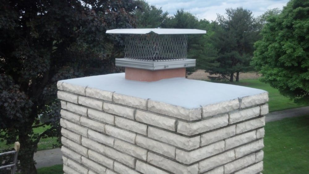 A brick chimney with a metal grille on top of it.