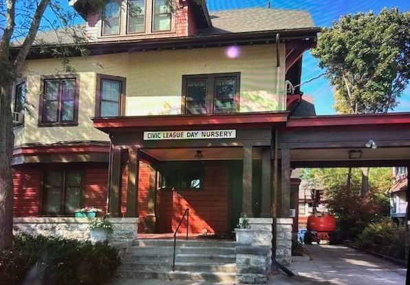 Two-story building with a red porch and sign that says 