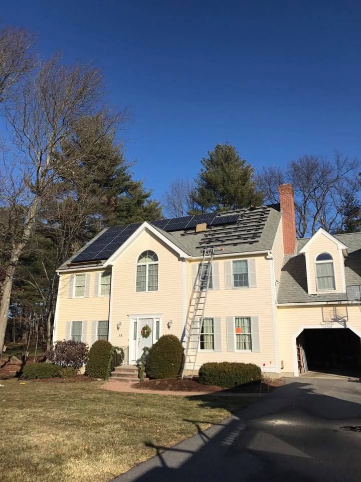 Two-story cream house with a ladder on the roof and a driveway leading to an attached garage.