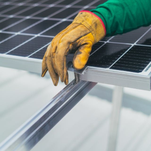 Gloved hand installing a solar panel on a metal frame