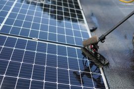 Pressure washer cleaning solar panels on a rooftop