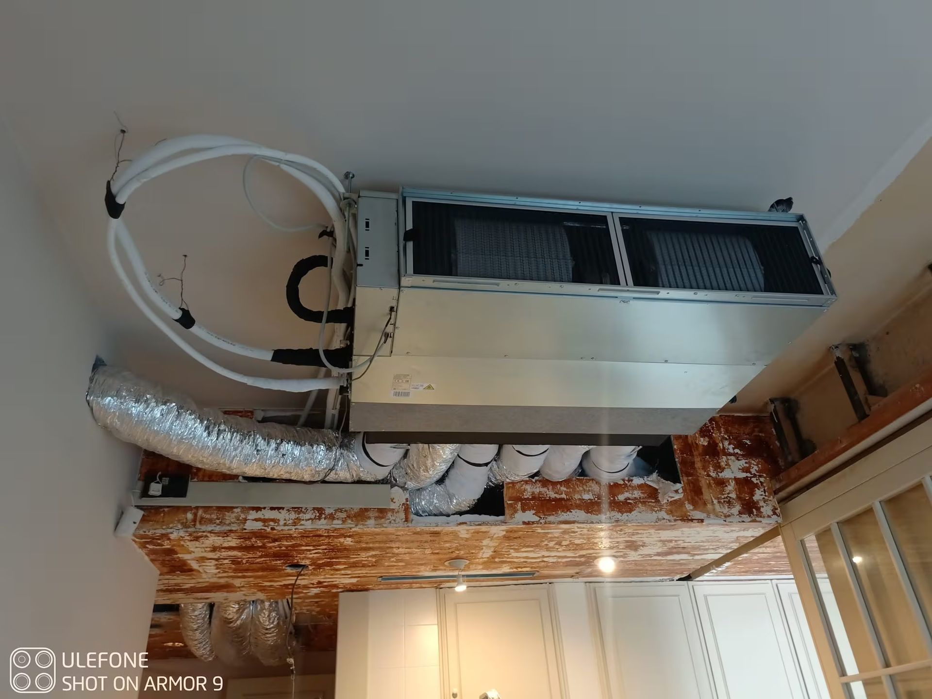 Unità di climatizzazione a soffitto con condotti a vista in una stanza in fase di ristrutturazione.