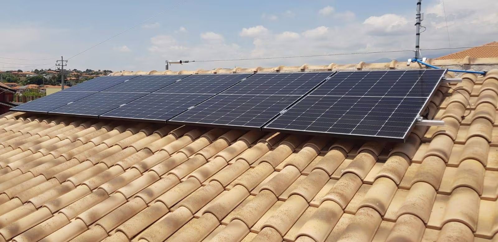 Pannelli solari installati su un tetto di tegole sotto un cielo sereno.