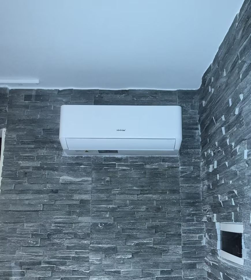 Condizionatore d'aria bianco a parete su un muro di pietra grigia all'interno di una stanza