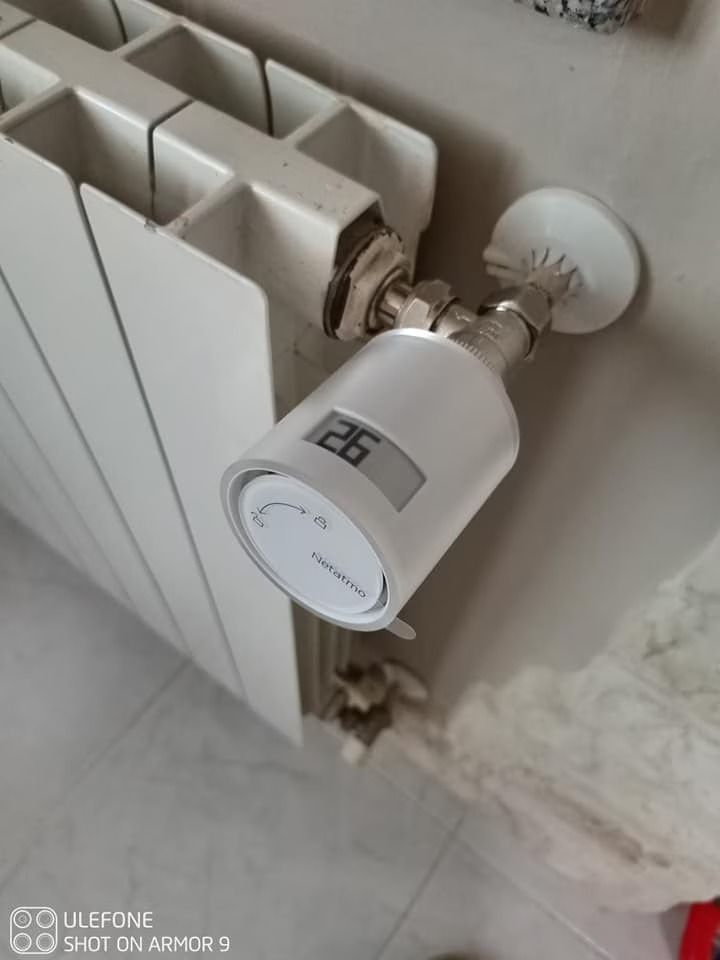 Valvola termostatica bianca per radiatore, installata su un radiatore bianco all'interno di un edificio, primo piano.