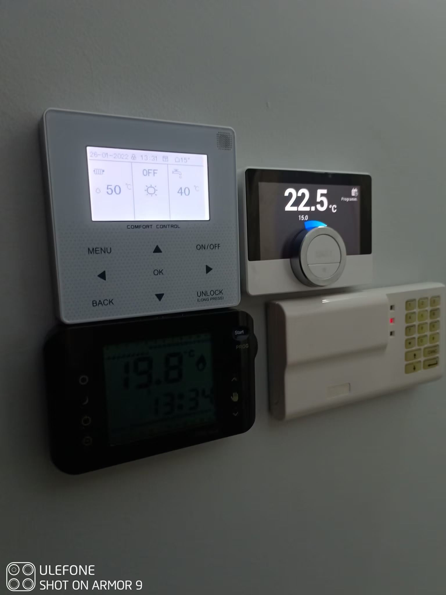 Termostati digitali a parete e pannelli di controllo con display della temperatura illuminati.