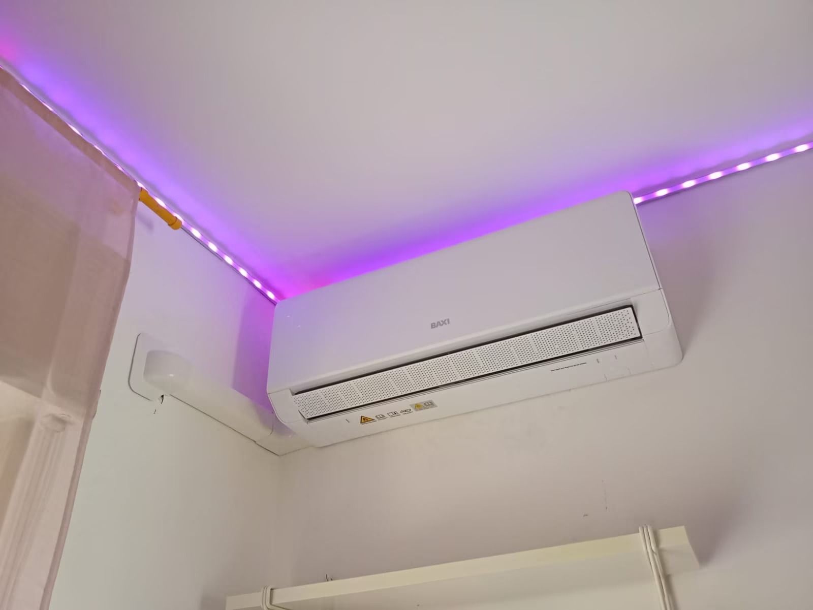 Condizionatore d'aria bianco a parete sotto luci a LED viola a soffitto in una stanza