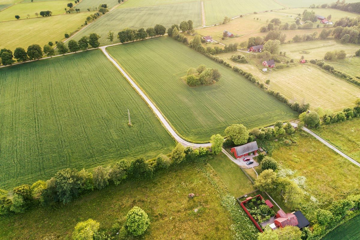 An aerial view of a farm with a house in the middle of a field.