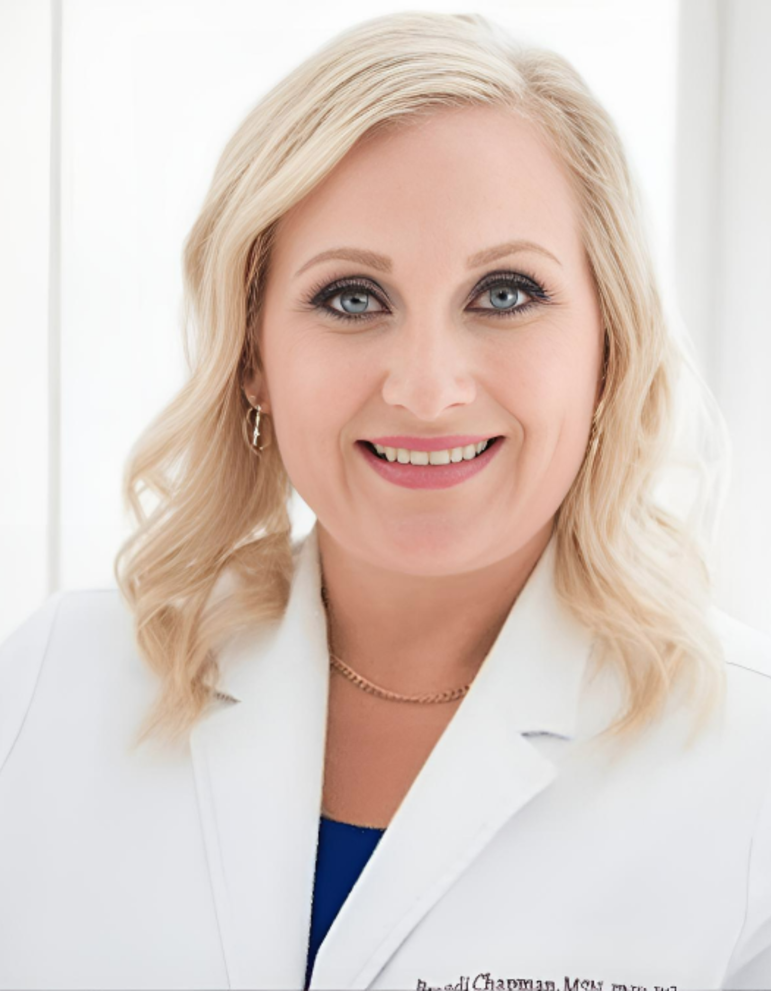 A woman in a white lab coat is smiling for the camera