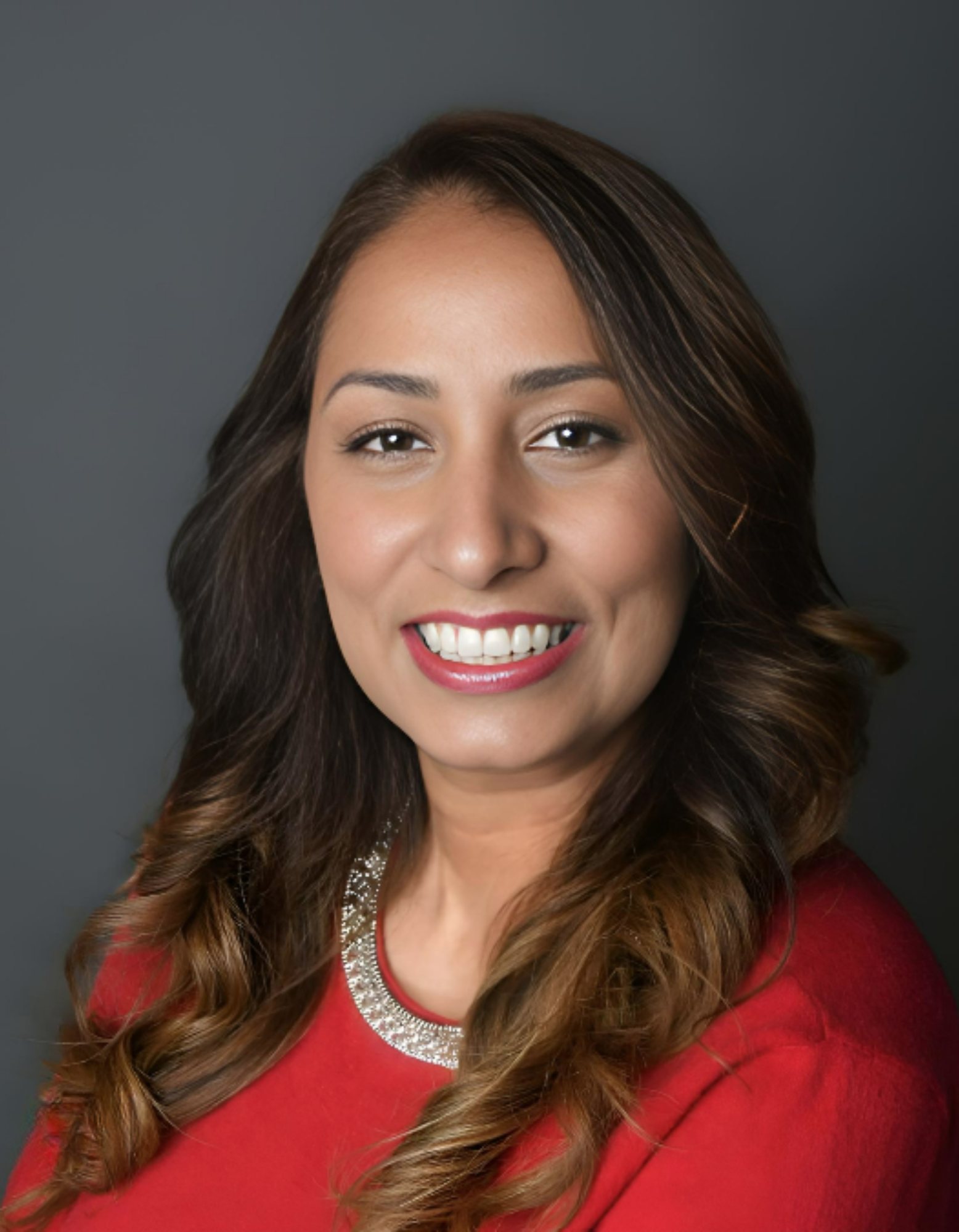 A woman in a red shirt is smiling for the camera.