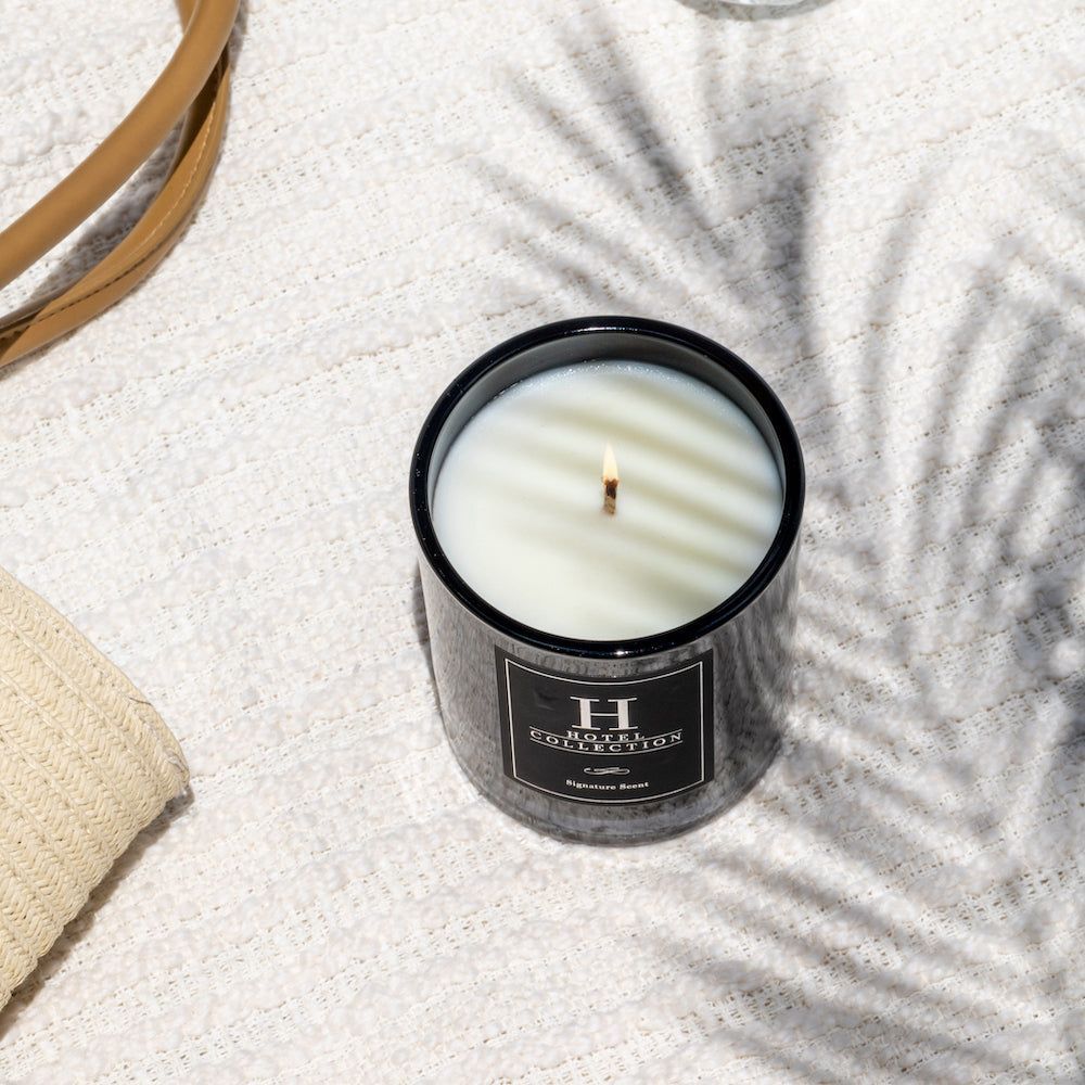 A candle is sitting on a table next to a palm tree leaf.