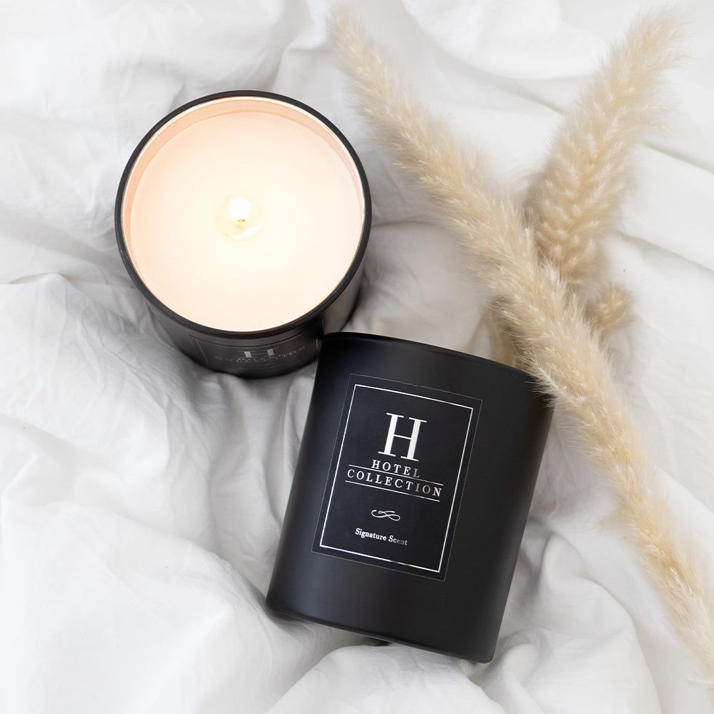 A candle is sitting on top of a bed next to a plant.