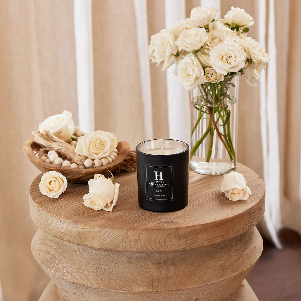 A candle is sitting on a wooden table next to a vase of flowers.