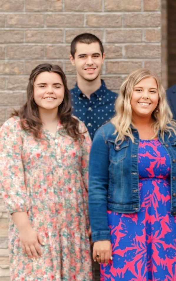 A group of people are posing for a picture in front of a brick building.