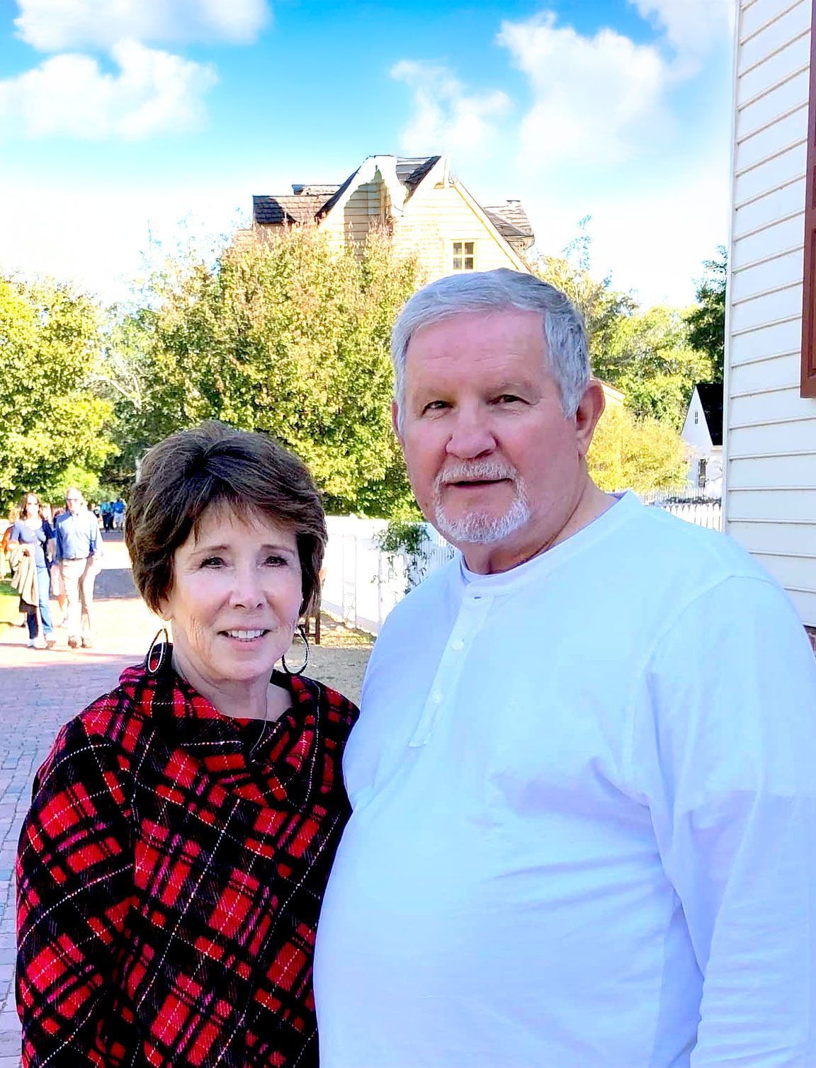 A man and a woman are posing for a picture in front of a building.