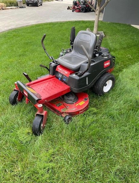 A Red and Black Lawn Mower is Sitting in the Grass — Ireland's Machinery Pty Ltd in Braemar, NSW