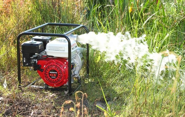 A Gas Powered Water Pump is Spraying Water in a Field — Ireland's Machinery Pty Ltd In Braemar, NSW