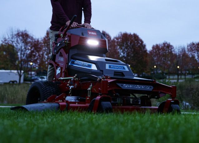 A Man is Riding a Lawn Mower on a Lush Green Field at Night — Ireland's Machinery Pty Ltd In Braemar, NSW