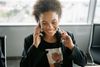 Smiling person on a phone call in a bright office, holding a coffee cup