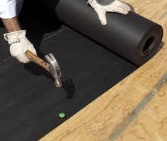 A person is using a hammer to hammer a roll of roofing.