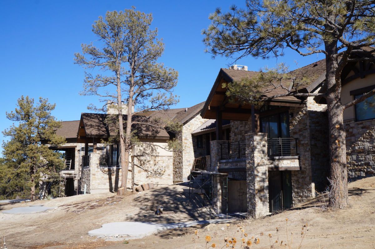 a couple of houses sitting on top of a hill surrounded by trees