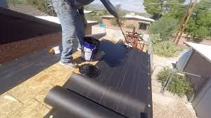 A man is painting a roof with a bucket of paint.