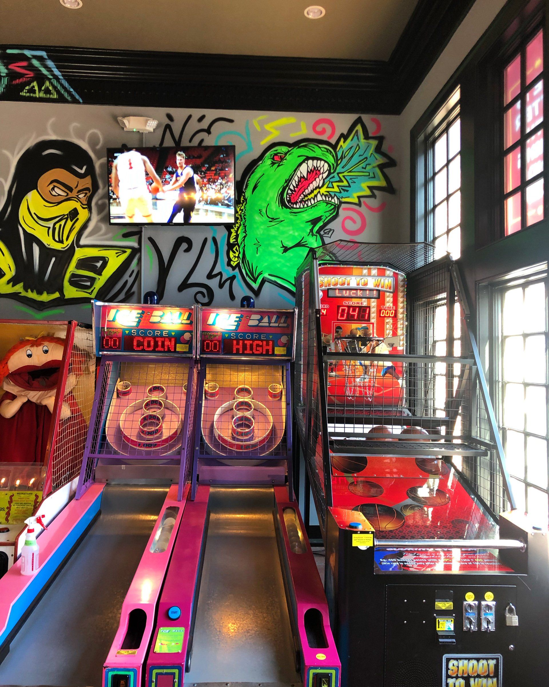 A room with a bunch of arcade games and graffiti on the wall